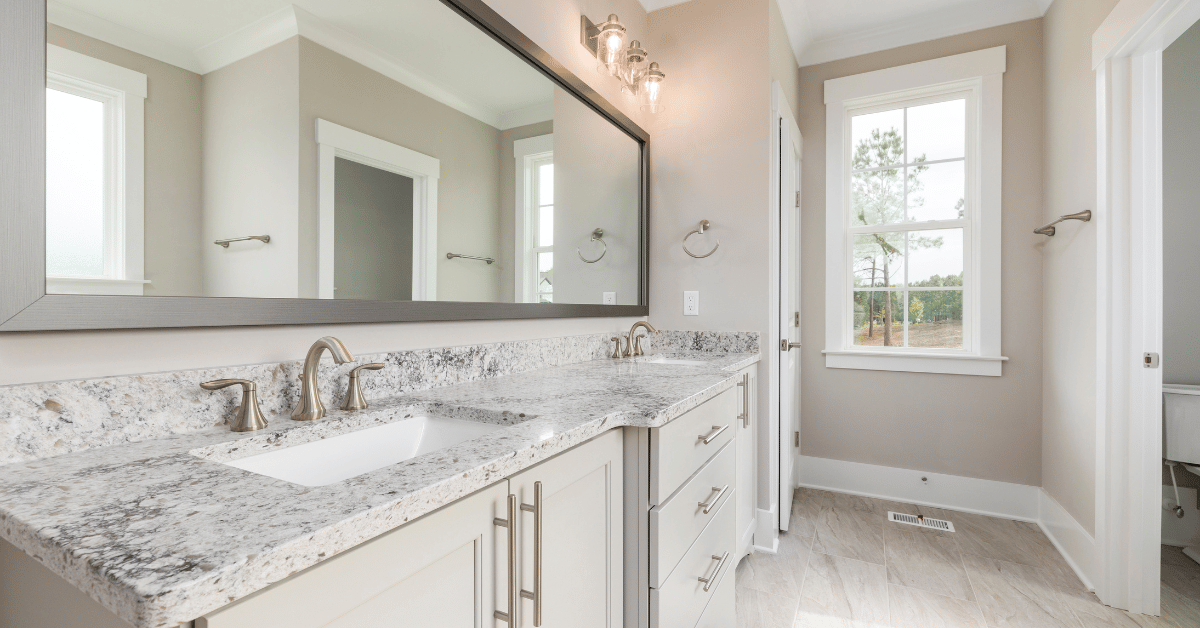 a well lit bathroom with a white marble countertop with an integrated sink